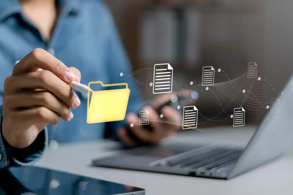 Persona interactuando con íconos digitales de una carpeta amarilla y archivos flotantes sobre una laptop, representando la modernización y la gestión de documentos en campamentos mineros